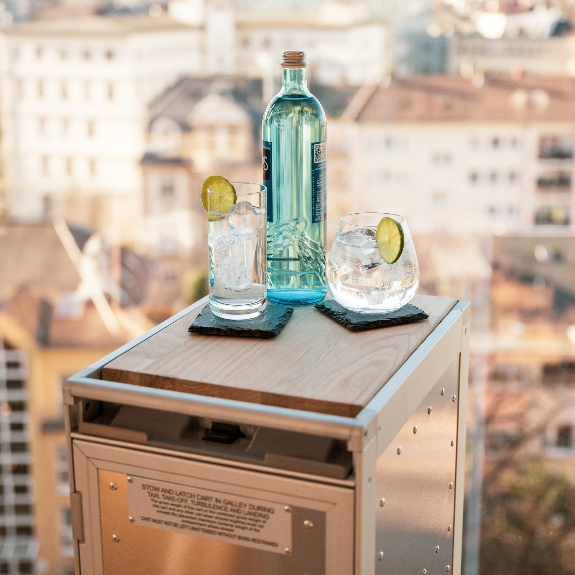 Wasserglas und Flasche auf Trolley mit Skyline Hintergrund