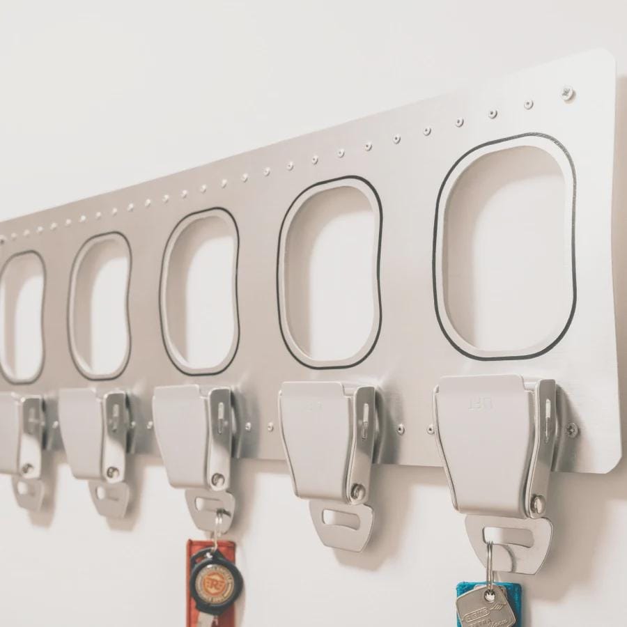 Detailaufnahme eines Aviation Schlüsselbretts aus Aluminium mit fünf Seatbelt Schlüsselhaltern – Luftfahrt Schlüsselleiste mit Flugzeug-Gurtschnallen
